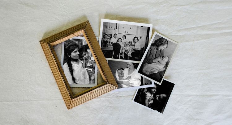 Are We Destined To Follow The People Who Raised Us? Multiple family photographs laid out on a linen spread.